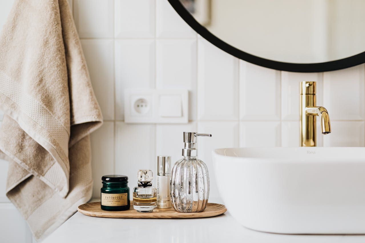 A bathroom with a white sink and a gold mirror.